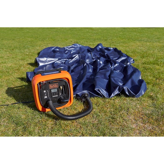 BLACKDECKER ASI400 portable air compressor next to a deflated blue inflatable, on grass outdoors.
