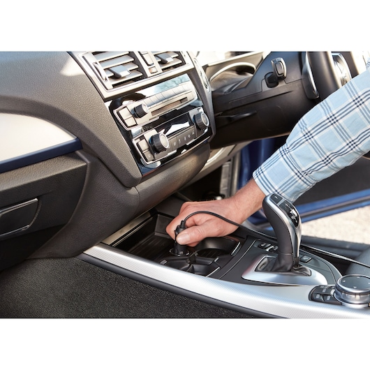 BLACKDECKER ASI400 car air compressor being plugged into vehicle power outlet, close-up view.