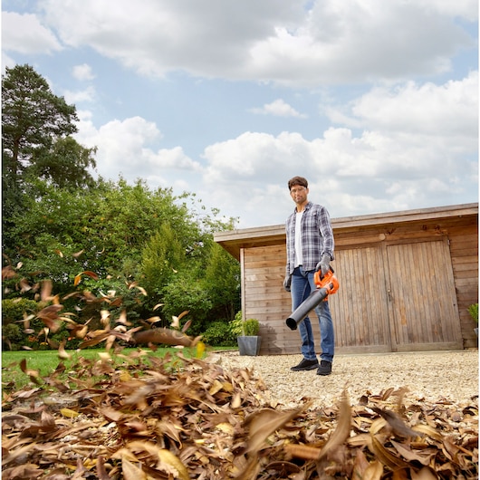 BLACKDECKER BCBL200B cordless leaf blower used outdoors near a wooden shed.