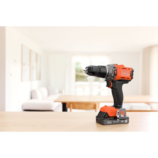 BLACK+DECKER cordless drill displayed on a table in a bright living room setting.