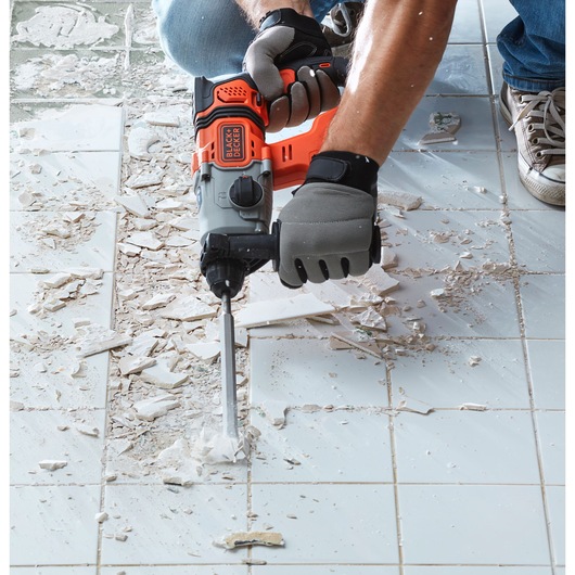 BLACKDECKER BCD900E2K rotary hammer in use breaking tiles on floor, close-up photography.