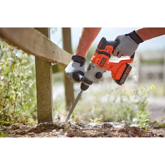 BLACKDECKER BCD900E2K cordless rotary hammer used outdoors, person wearing gloves breaking ground.