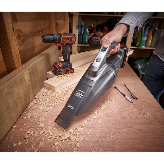 BLACKDECKER BCHV001C1 handheld vacuum cleaning wood shavings in workshop, cordless drill visible in background
