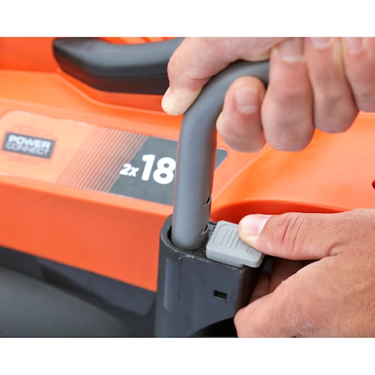 Photo of BLACKDECKER BCMW33182L2 lawn mower handle being adjusted, close-up of orange body and hand.