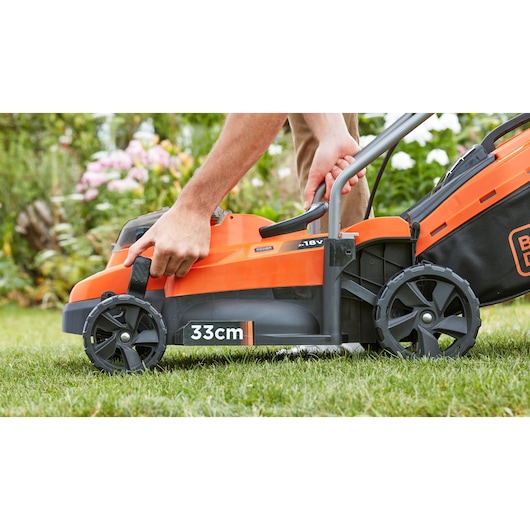 Photo of BLACKDECKER BCMW33182L2 cordless lawn mower, orange and black, side view with 33cm cutting width.