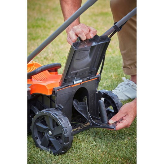BLACKDECKER BCMW33182L2 lawn mower close-up showing rear discharge area with open flap on grass.