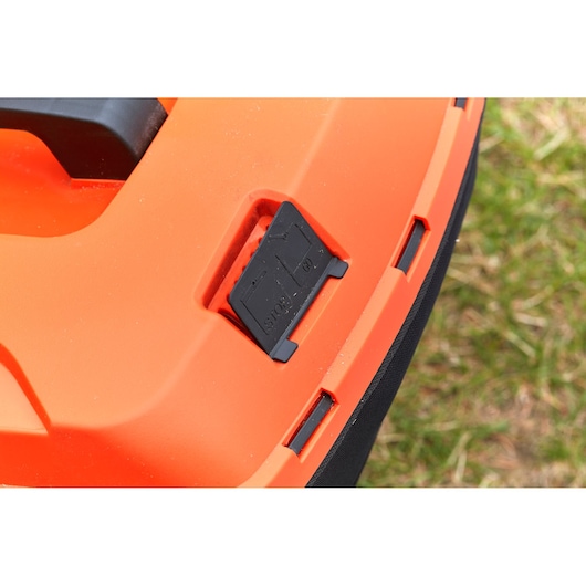 Close-up photo of BLACK+DECKER BCMW33184L2 orange lawn mower body with black control switch detail.