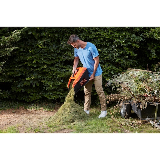 Photo of BLACKDECKER BCMW3318N lawn mower grass box being emptied outdoors.