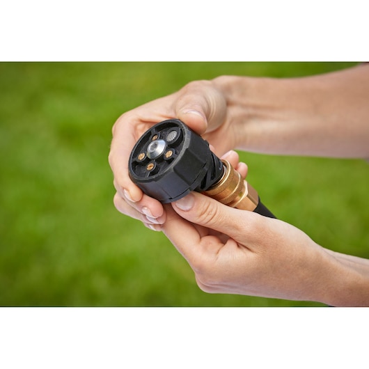 BLACKDECKER BCPC18D1 garden hose nozzle held in hand, close-up view outdoors.