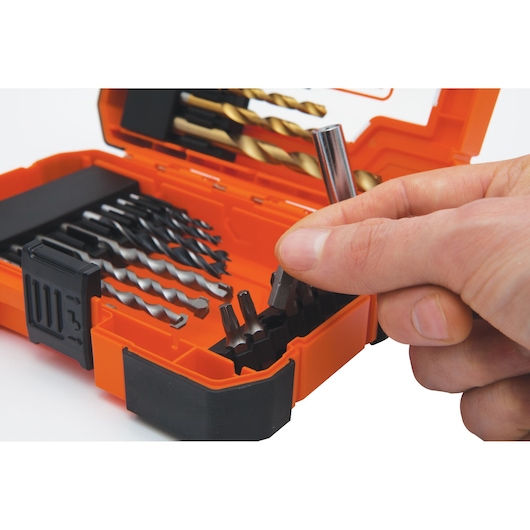 A hand selecting a bit from an orange BLACK+DECKER drill and bit set case containing various drill bits and screwdriver bits.