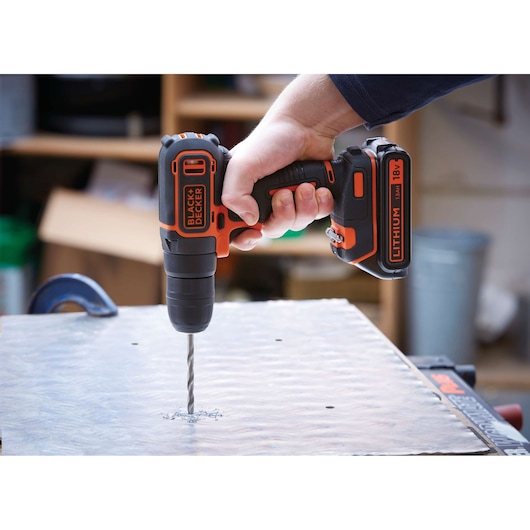 BLACKDECKER BDCD18K cordless drill in use drilling into metal surface, close-up side angle.