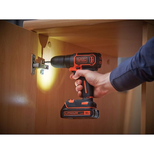BLACKDECKER BDCD18 cordless drill with LED light in use on cabinet hinge, close-up photography.