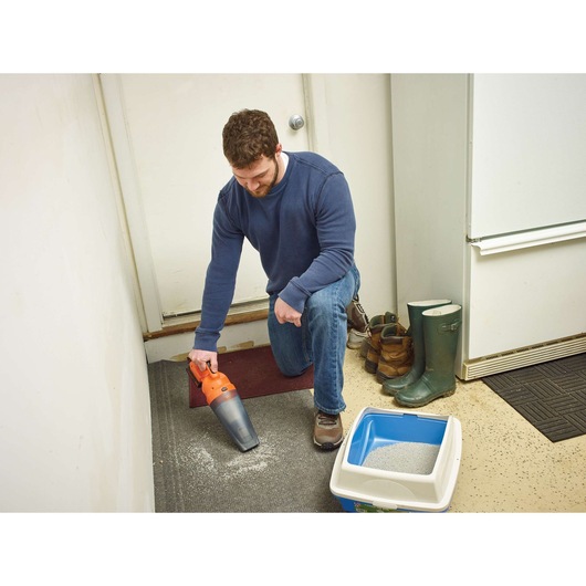 BLACKDECKER handheld vacuum BDCDB18N cleaning spilled litter near boots and a litter box in a mudroom.