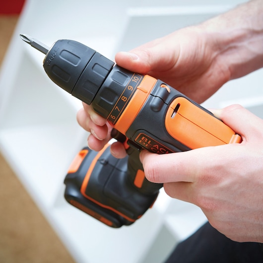 BLACK+DECKER BDCDD12B cordless drill in black and orange held in hands, close-up view.