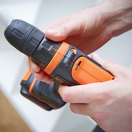 BLACKDECKER BDCDD12KB cordless drill with orange and black body held in hand, close-up view.