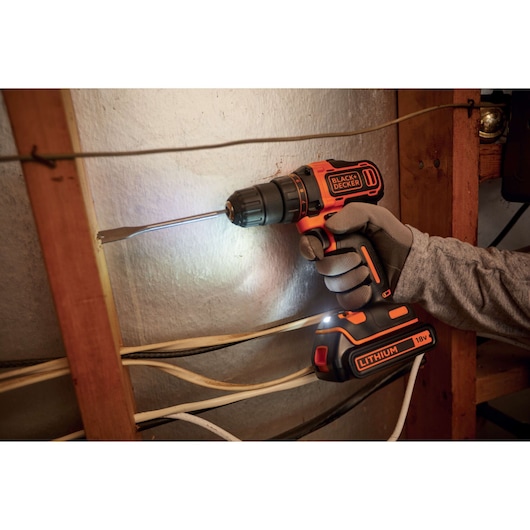 BLACK+DECKER BDCDD186B cordless drill driver in use, drilling wood, visible 18V lithium battery.