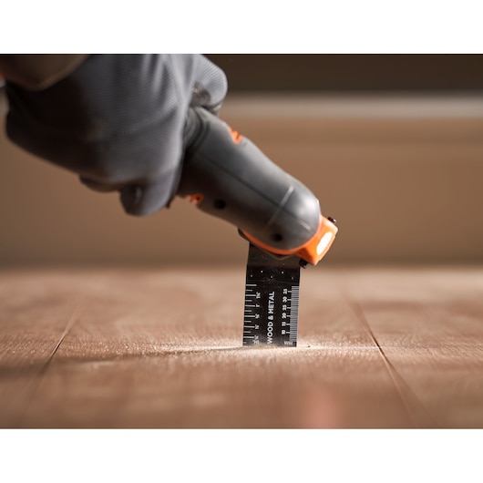 BLACKDECKER BDCOS18N oscillating tool cutting wood floor, close-up photography.
