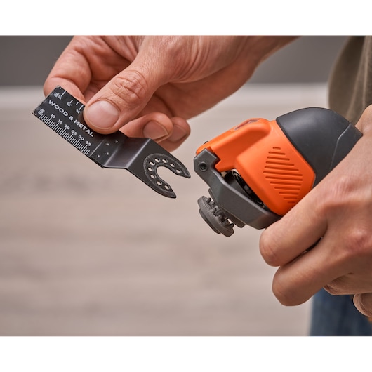 BLACKDECKER BDCOS18N oscillating multi-tool close-up with a hand attaching a wood and metal saw blade.