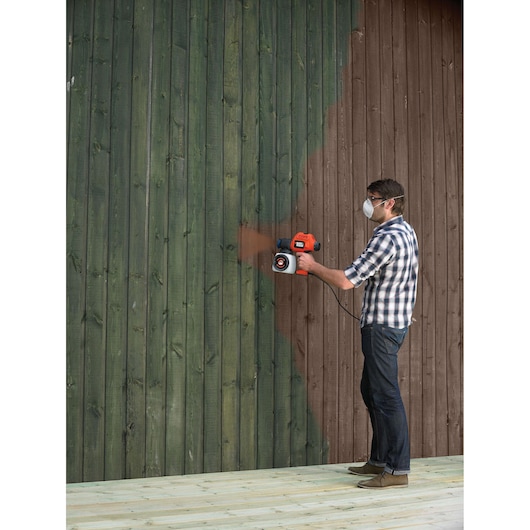 BLACKDECKER BDPS200 paint sprayer used on a wooden wall, product in side view.