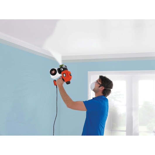 BLACKDECKER BDPS400 paint sprayer used on ceiling, orange and black, indoor setting.