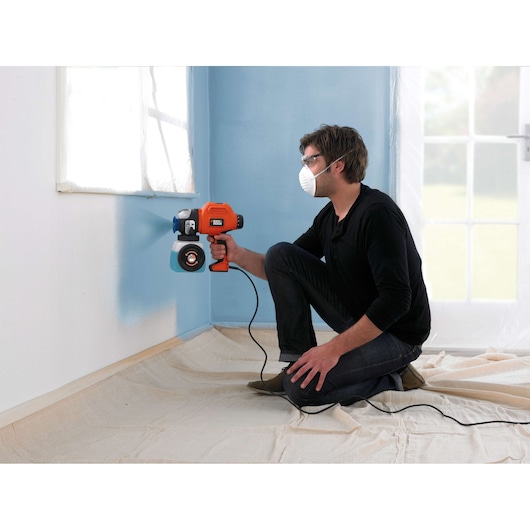 Photo of BLACKDECKER BDPS400 paint sprayer in use, painting a blue wall in a room.