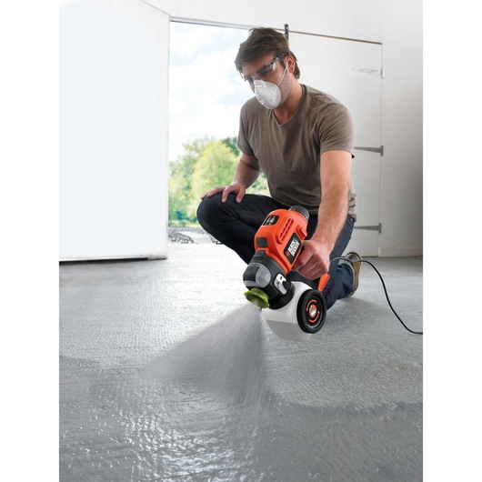 BLACKDECKER BDPS400 paint sprayer applying coating to concrete floor, handheld electric model.