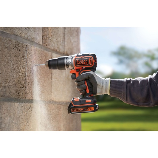 BLACKDECKER BL188KB cordless drill in use on stone wall, orange and black design, Lithium 18V battery.