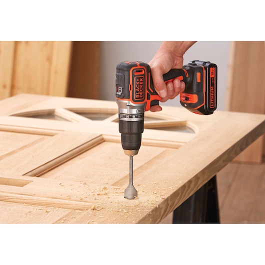 BLACK+DECKER BL188K cordless drill in use on wooden door, close-up view, orange and black design.