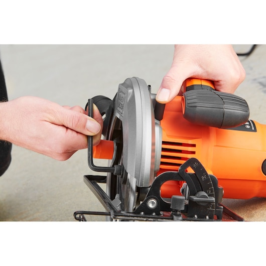 Photo of BLACKDECKER CS1550 circular saw being adjusted, orange and black body, side angle.