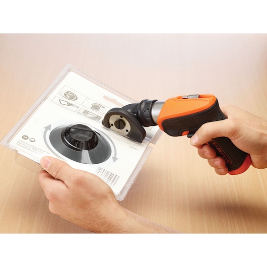 Photo of BLACK+DECKER CSCA3 electric cutting tool being used to open plastic packaging on a wooden surface.