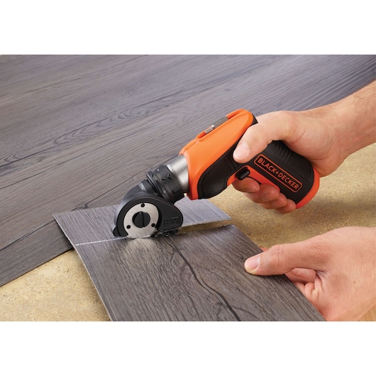 BLACKDECKER CSCA3 compact rotary cutter tool in use, cutting vinyl flooring.