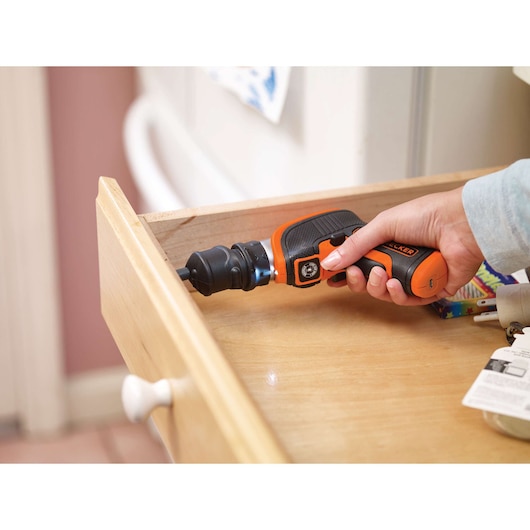 BLACKDECKER CSOA2 orange cordless screwdriver used on a wooden drawer.
