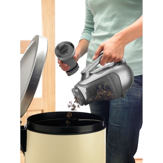Photo of BLACKDECKER DV1815EL handheld vacuum being emptied into a bin by a person.