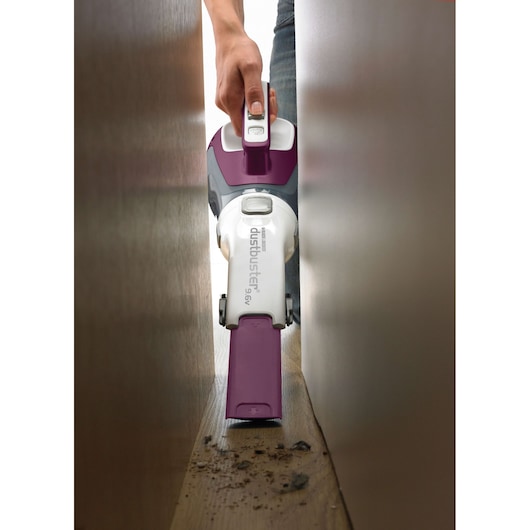 BLACKDECKER DV9610ECN handheld vacuum cleaning debris between narrow wooden surfaces, front angle.