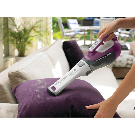 BLACKDECKER DV9610ECN handheld vacuum in use on a purple cushion indoors, showing cyclonic action feature.