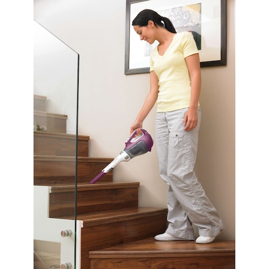 BLACKDECKER DV9610ECN handheld vacuum in use cleaning wooden stairs indoors.