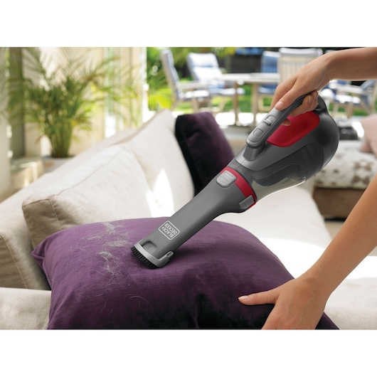 BLACKDECKER DV9610N handheld vacuum cleaning pet hair from a purple sofa cushion indoors.