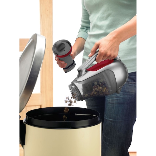 BLACKDECKER DV9610N handheld vacuum emptied into trash bin, person holding vacuum and filter.