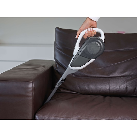 Photo of BLACKDECKER DVJ215J handheld vacuum cleaner cleaning between brown leather sofa cushions.
