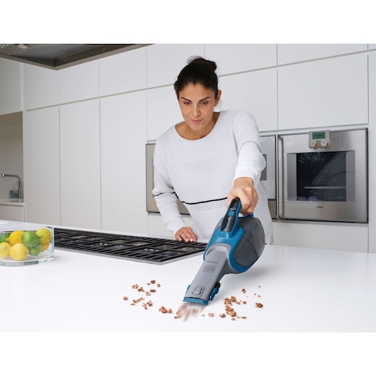 BLACKDECKER DVJ320J handheld vacuum cleaning crumbs on kitchen counter.