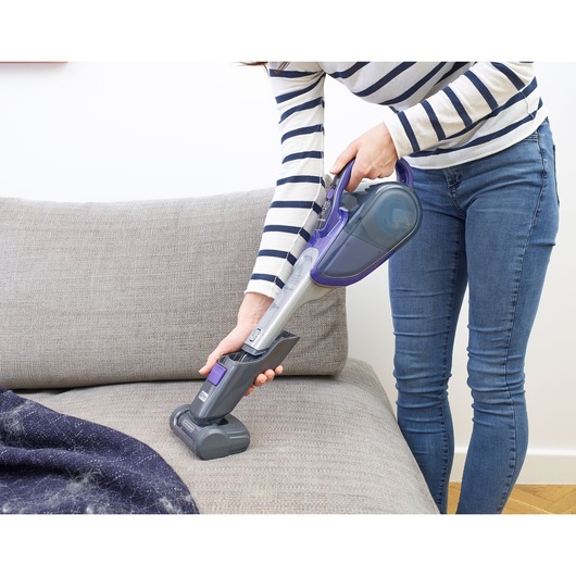 BLACKDECKER DVJ325BFSP handheld vacuum cleaning grey sofa with pet hair attachment.