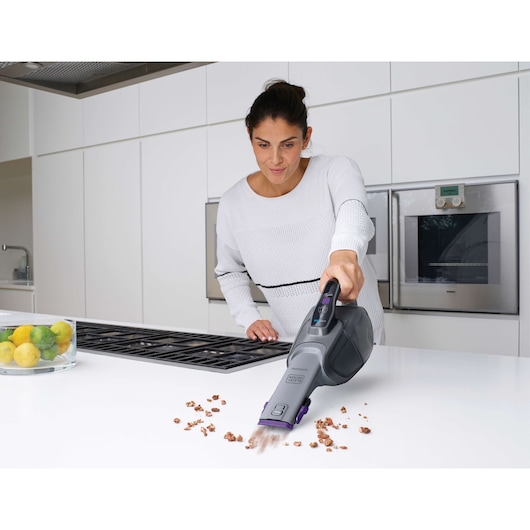 BLACKDECKER DVJ325BFS handheld vacuum cleaning crumbs on kitchen counter.