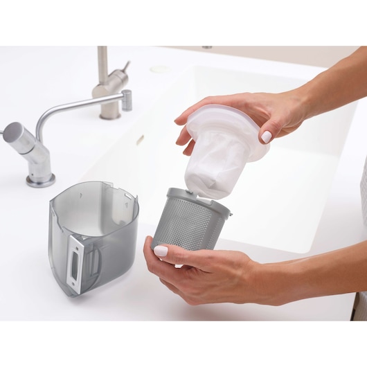 BLACKDECKER DVJ325BFS vacuum filter and dust container near a sink, shown being cleaned.