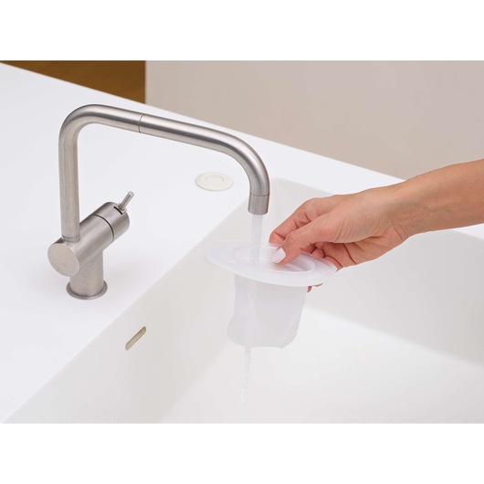 Photo of BLACKDECKER DVJ325BFS filter being rinsed under a kitchen faucet in a white sink.