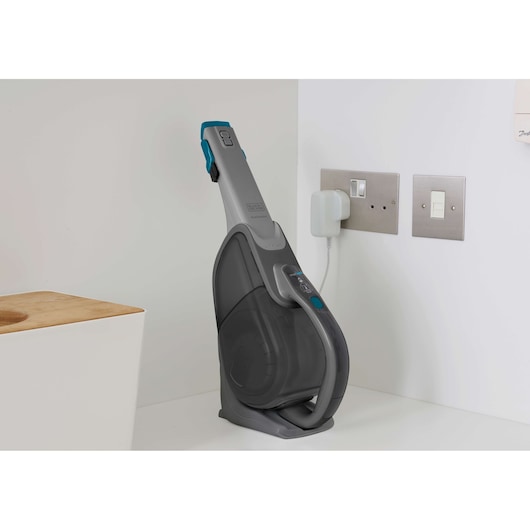 BLACKDECKER DVJ325BF handheld vacuum cleaner in charging dock on white countertop, side angle.