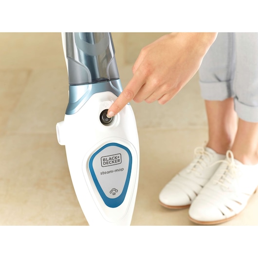 BLACK+DECKER steam mop FSM1605 close-up of power button being pressed on tiled floor.