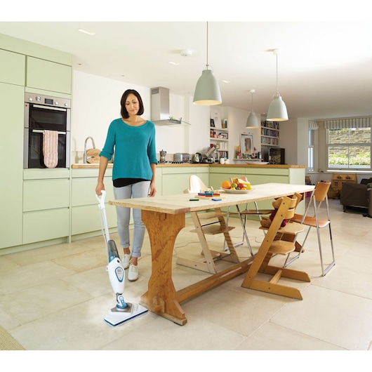 Photo of BLACKDECKER FSM1616 steam mop cleaning light tile floor in a modern kitchen with wooden dining table.