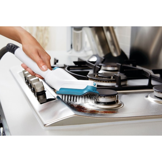 BLACKDECKER FSMH13101SM steam cleaner with brush attachment cleaning stove top grime.