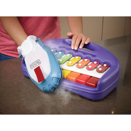 BLACK+DECKER FSMH1351SM steam cleaning glove cleaning a colorful plastic xylophone on a countertop.