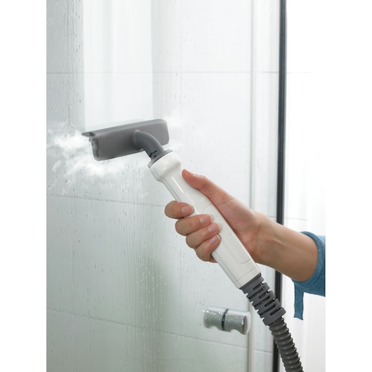 BLACKDECKER FSMH1351SM handheld steam cleaner cleaning bathroom glass surface, close-up.
